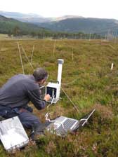 Photograph of a scientist using equipment to measure soil respiration at Invercauld