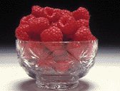 Photograph of a glass bowl full of raspberries