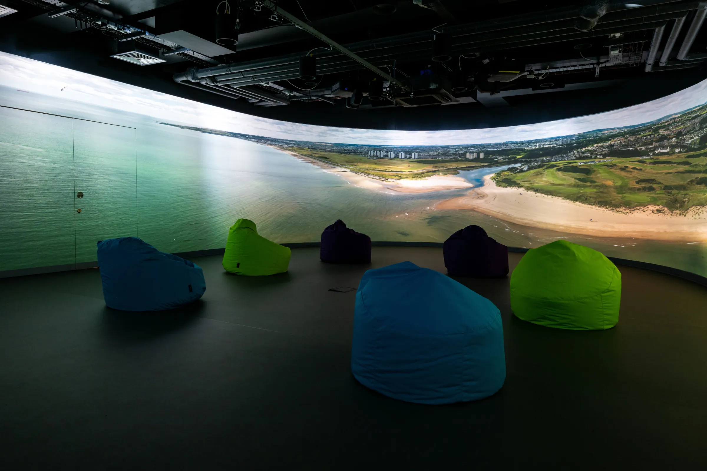 Beanbag seating inside the Immersive Suite at the Hutton Hub, with a 360 degree screen showing a panoramic coastal landscape