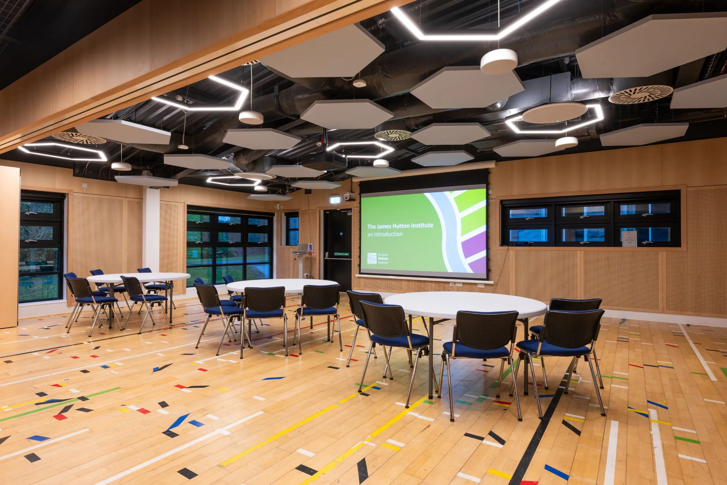 Conference Suite 1A and 1B at the Hutton Hub set out cabaret style with round tables facing a large screen